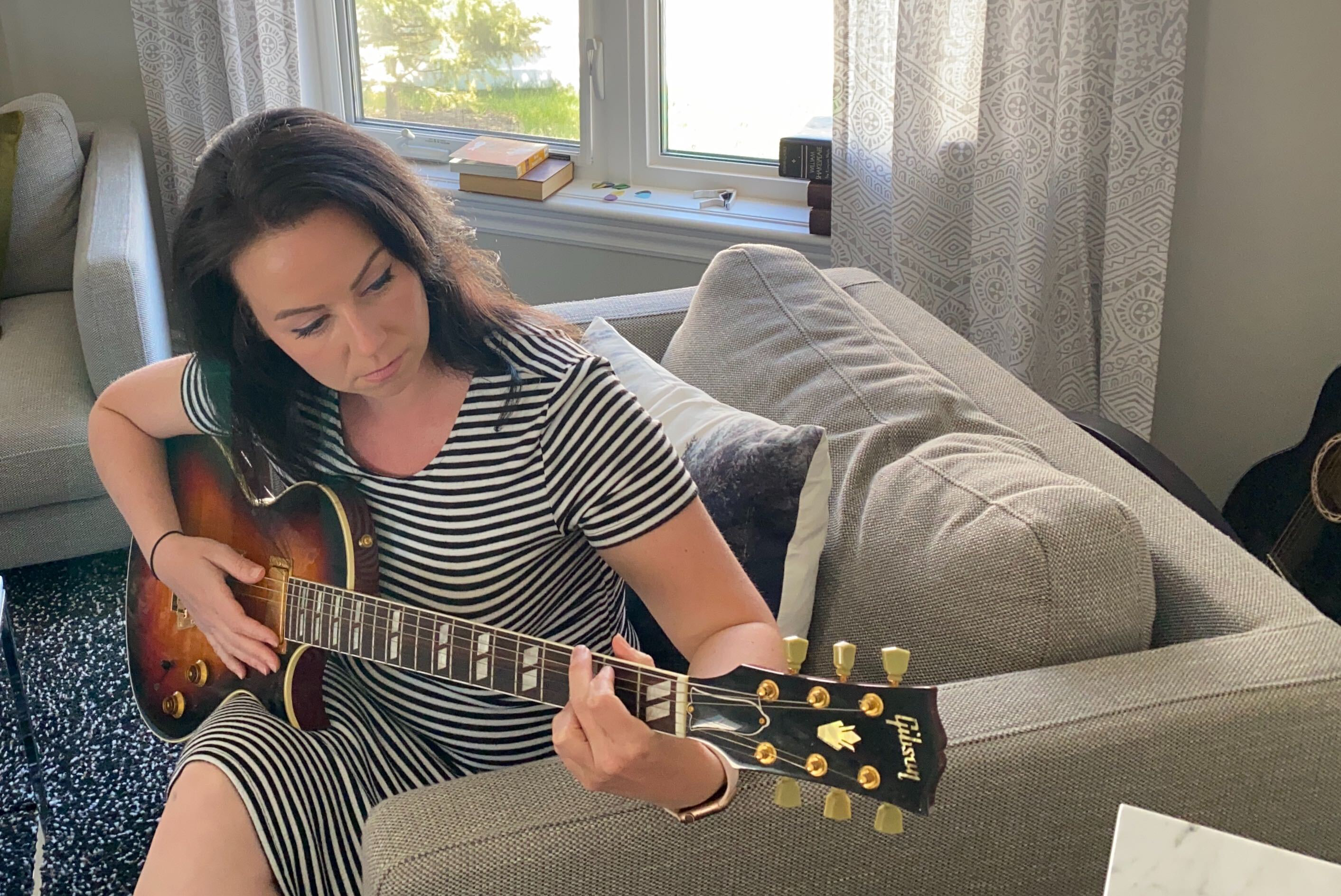 Bandzoogle CEO Stacey Bedfor plays guitar in her home.